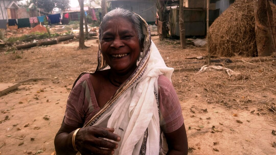 an old Indian woman standing outdoors and smiling