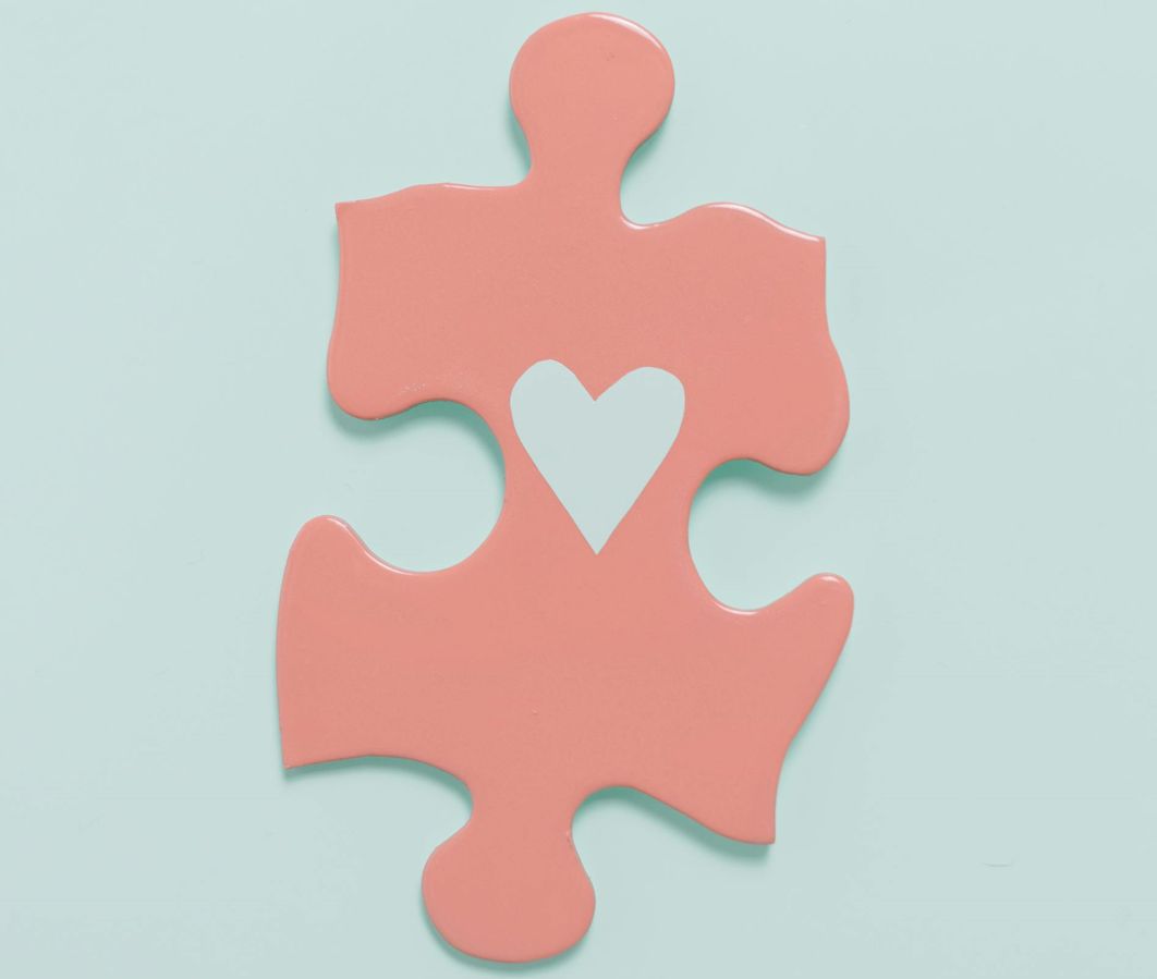 a pink autism puzzle piece symbol with a heart inside