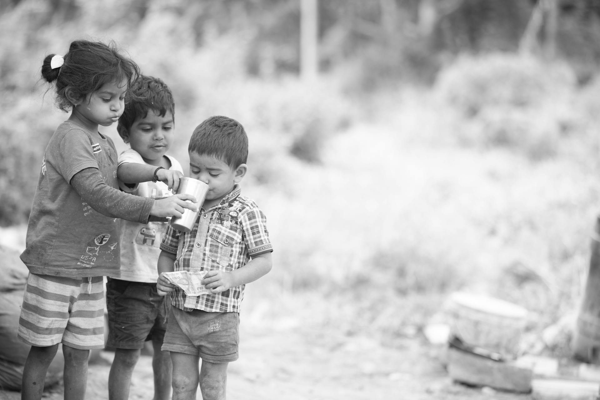 a black and white photo of three children outdoors