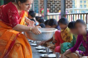 a woman serving food to children