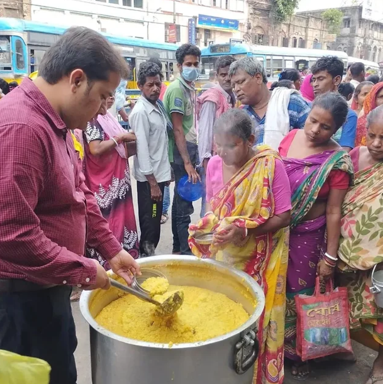 a man cooking and serving food to people in need