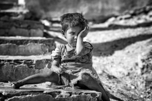 A black and white photo of a lonely child outdoors in distress
