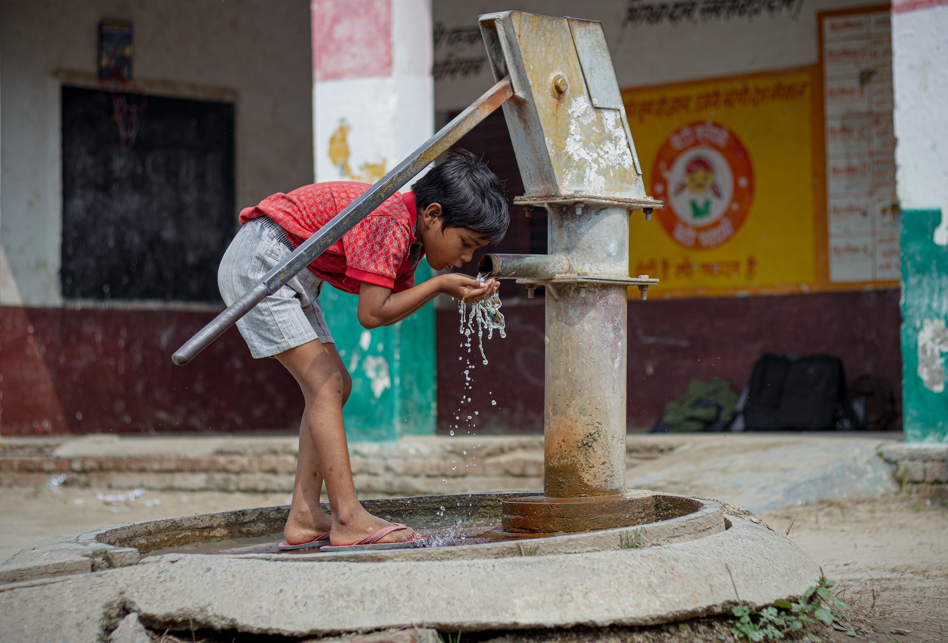 a child in India drinking from a well