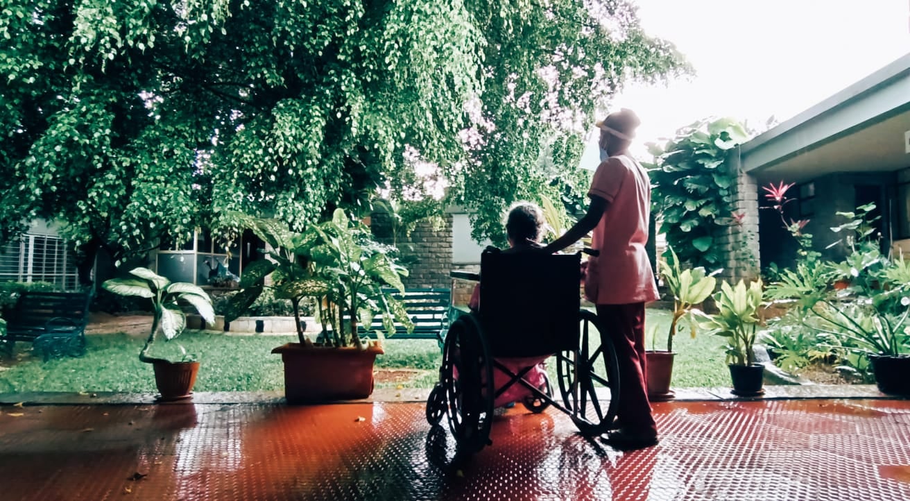 a doctor at Karunashraya helping a cancer patient in a wheelchair