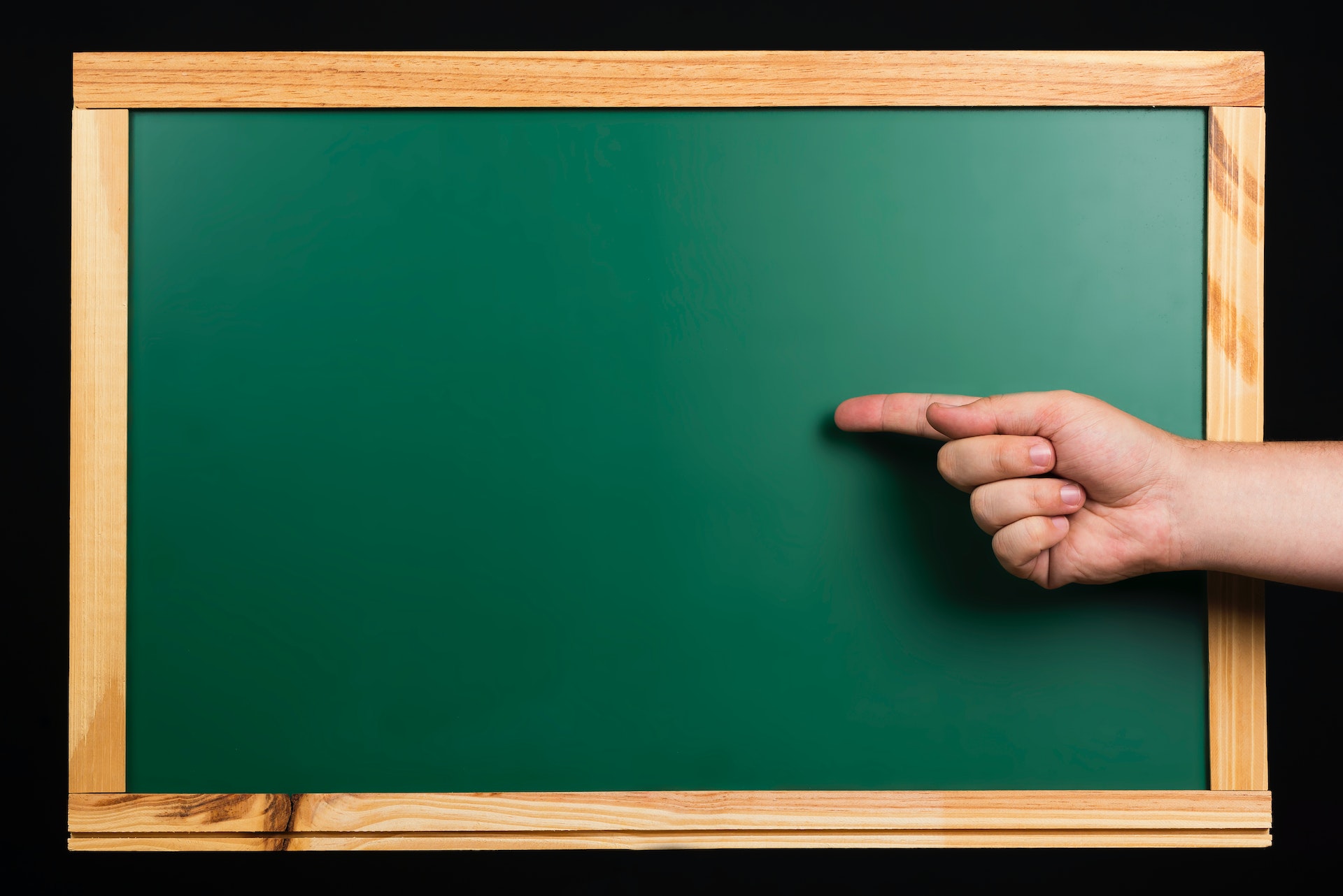a green chalkboard with a hand pointing toward it