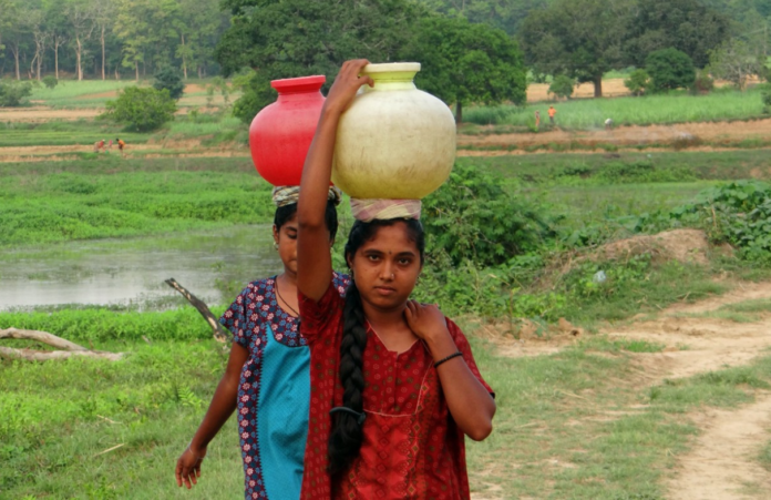 two rural women in India carrying water pots