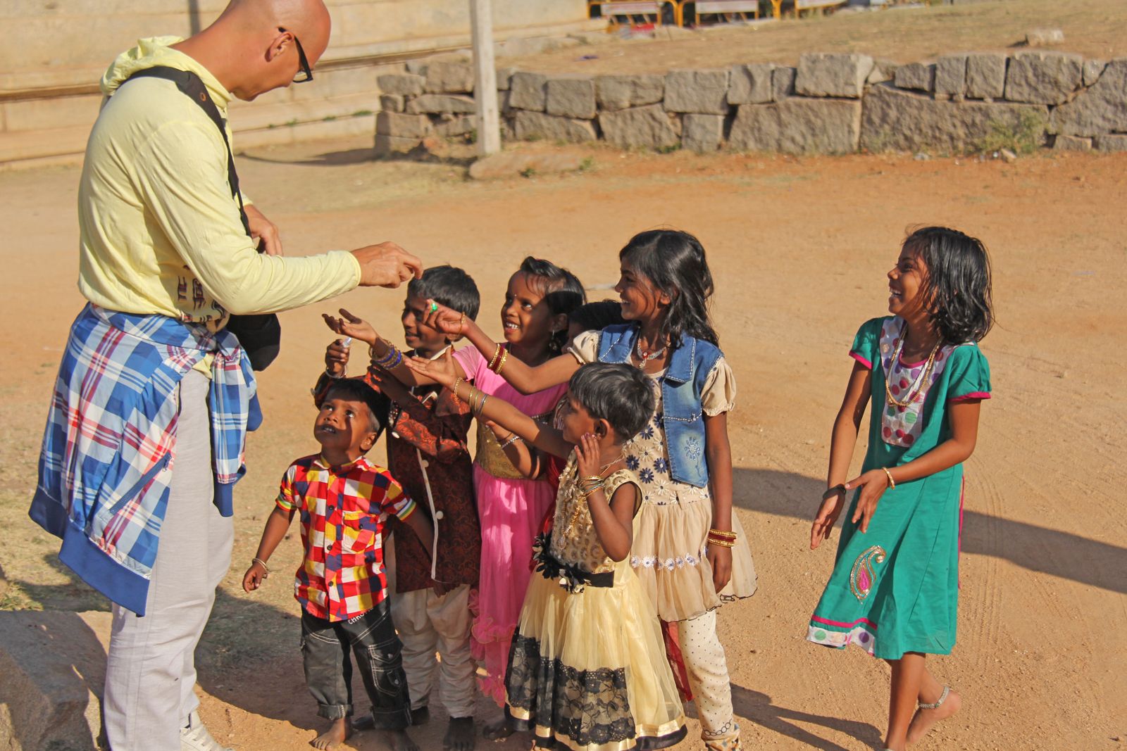 an elderly Indian man handing out sweets to children