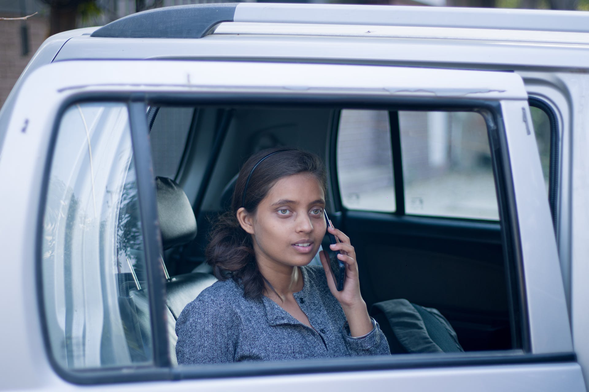 a young woman in the backseat of a car on her phone