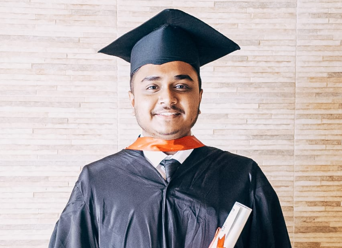 an Indian college graduate with a cap and gown and diploma