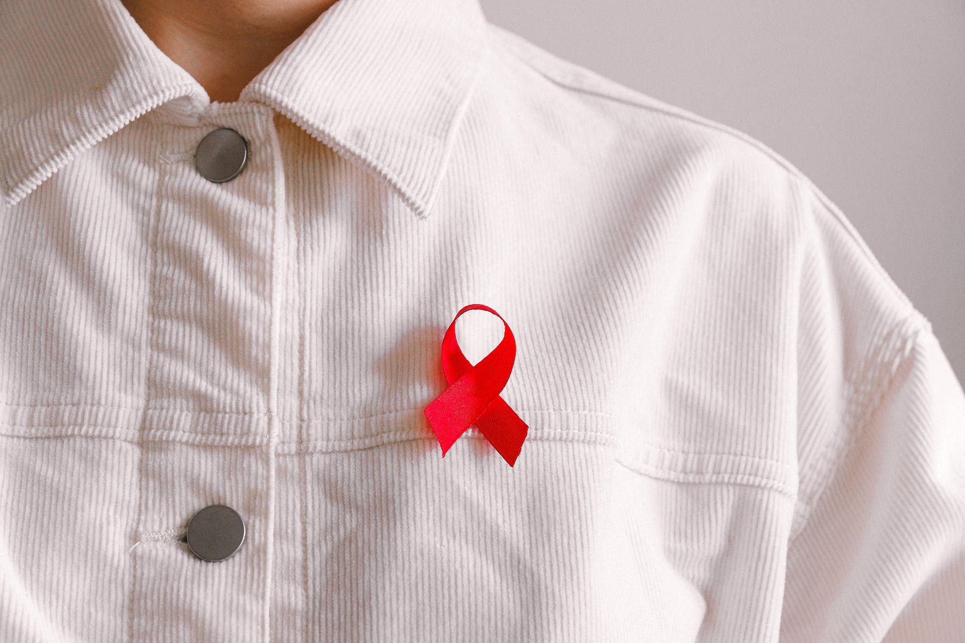 a red ribbon pinned to a man's white shirt