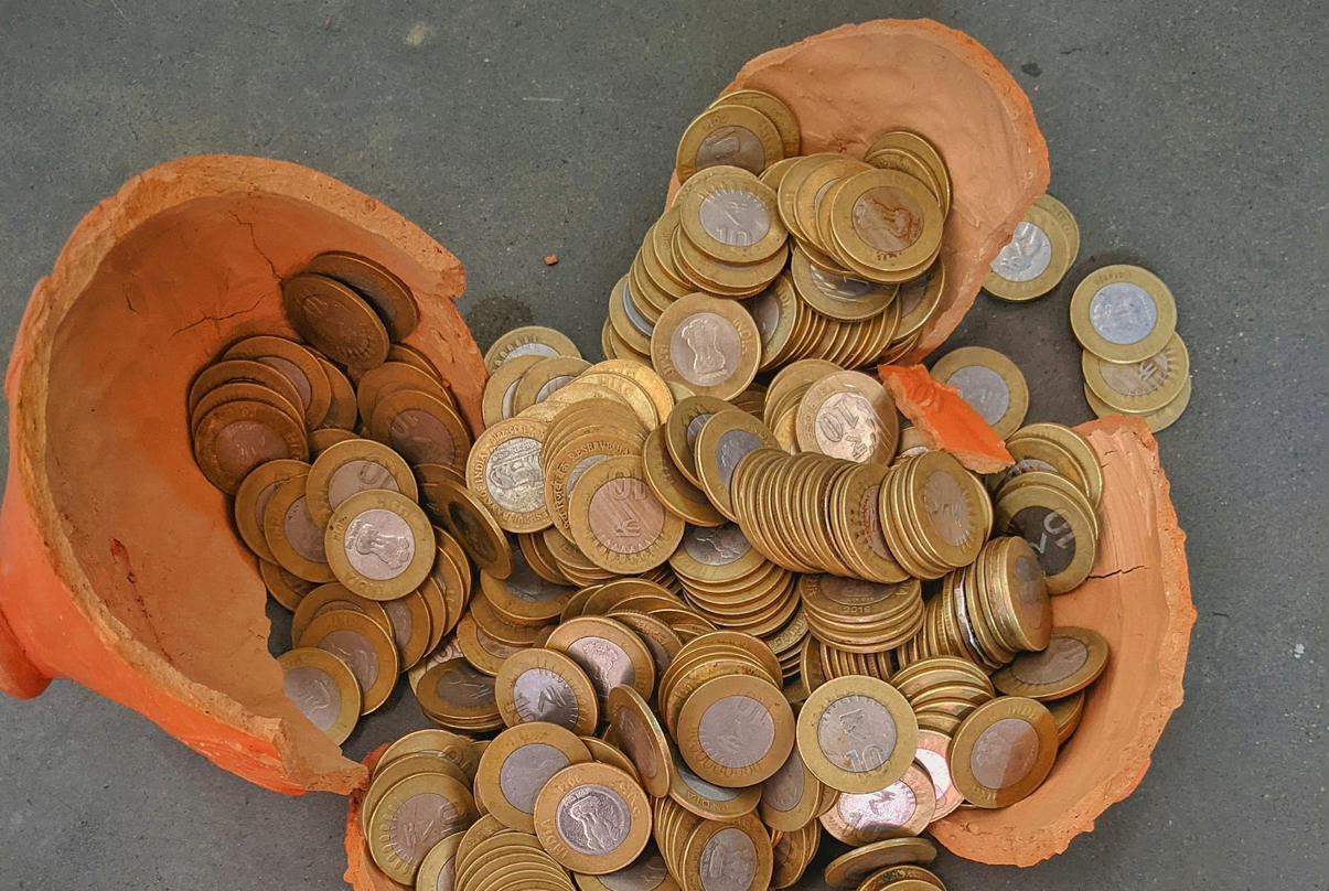 a broken clay pot with Indian coins