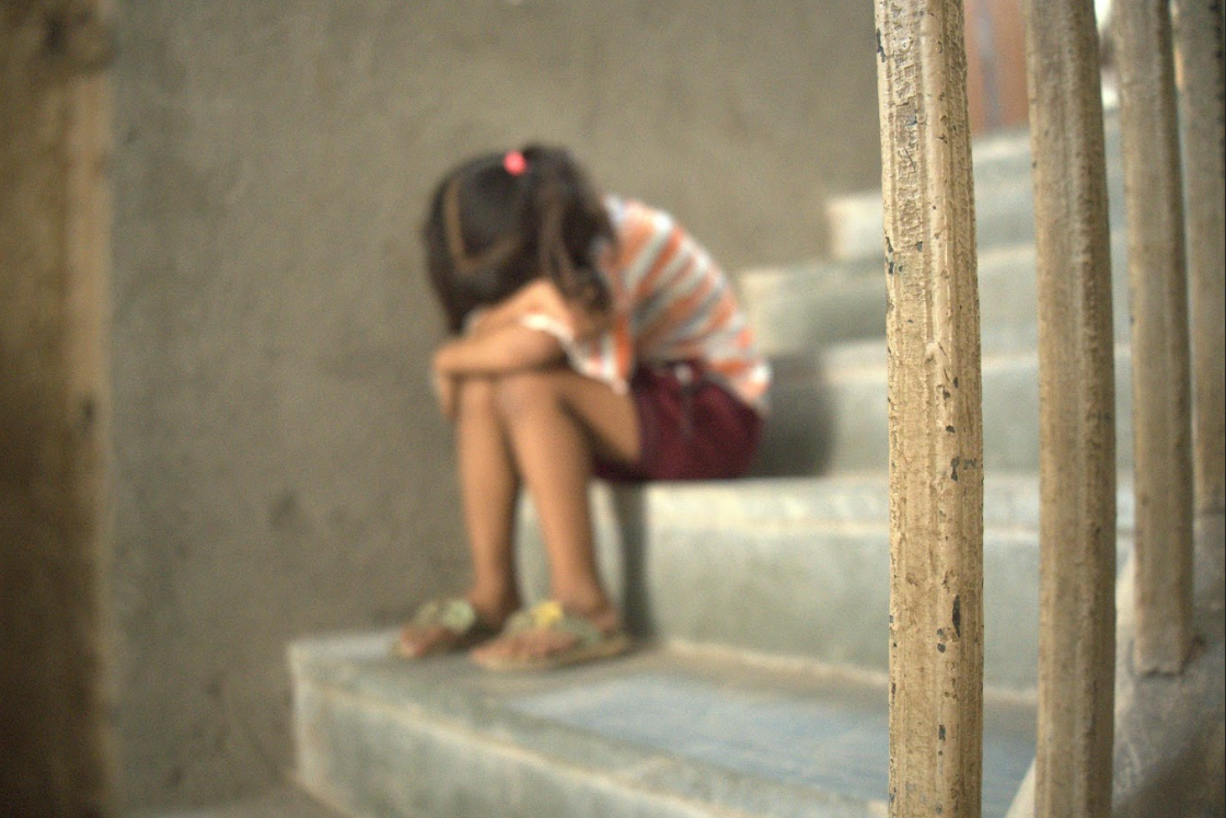 a child sitting on a staircase with her head in her lap