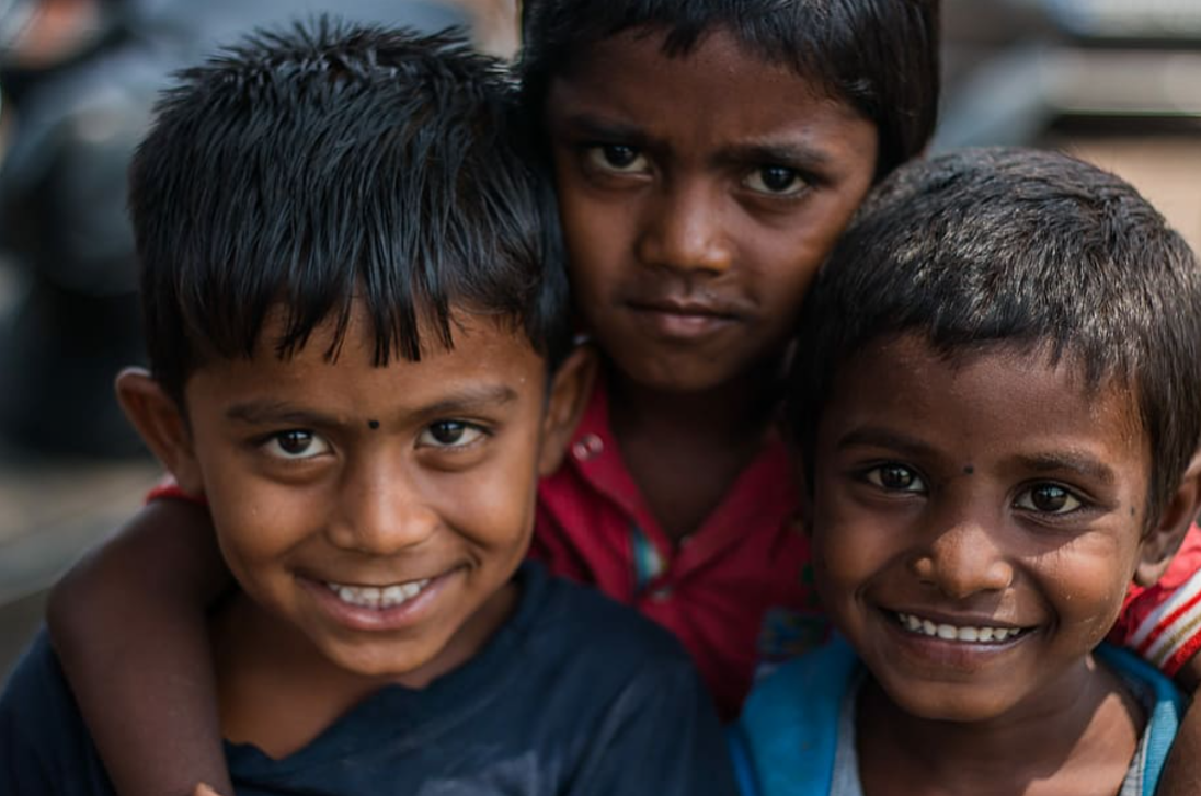 three Indian children looking at the camera and smiling