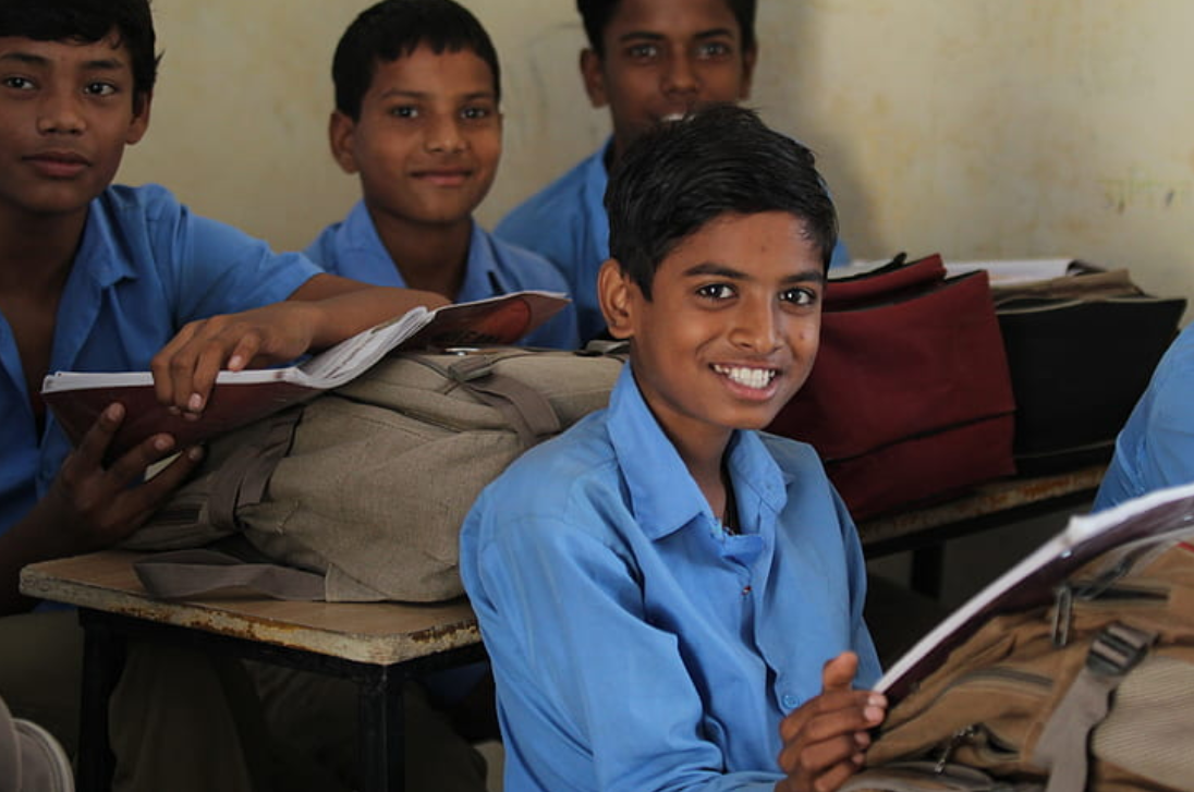 a classroom of school children smiling at the camera