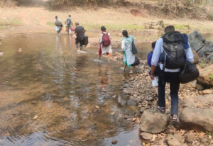 a group of NGO workers crossing a stream