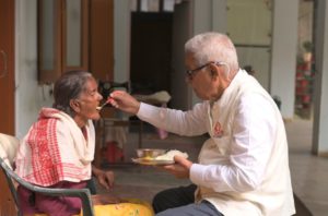 an elderly man feeding an elderly woman