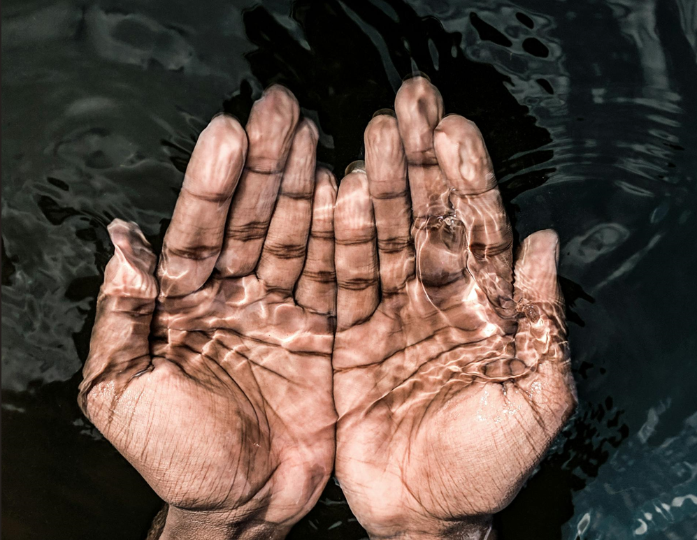 cupped hands under transparent water