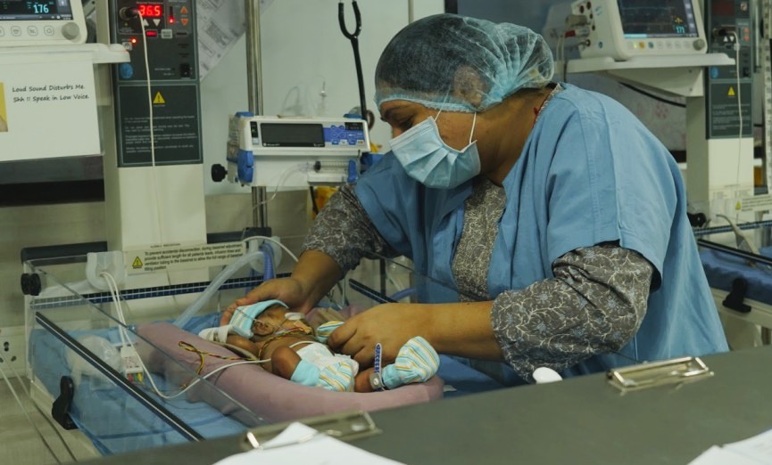 a medical professional looking at a baby in the ICU