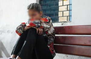 a sad young girl sitting on a bench