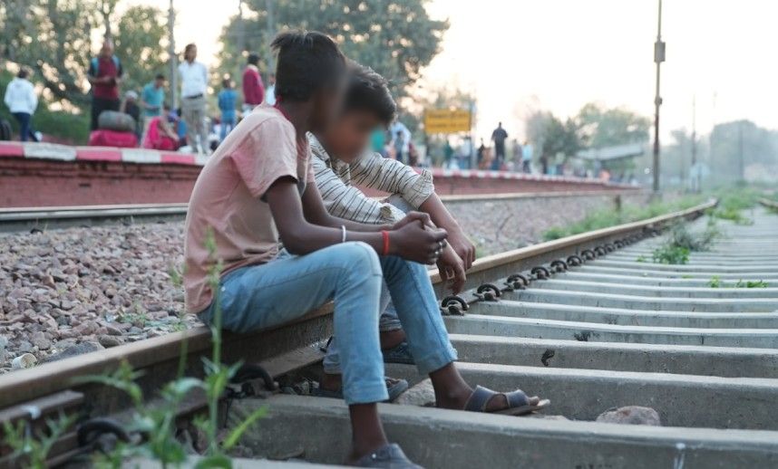 two young boys sitting on railway tracks