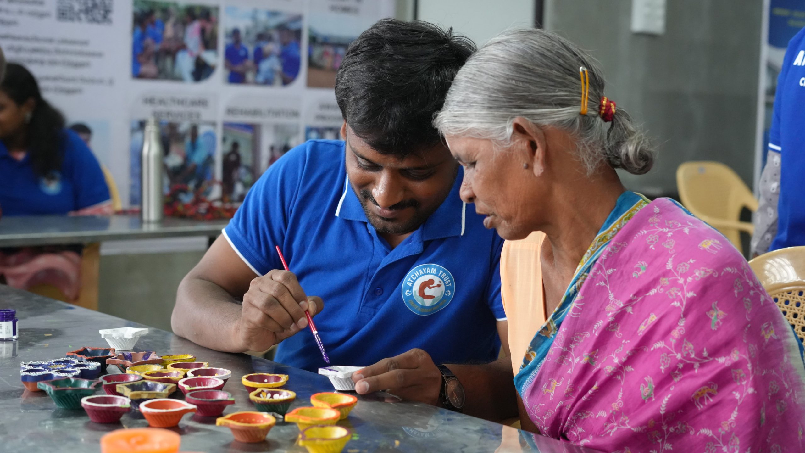 a young man helping an old woman paint