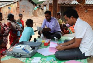 two men treating children in a village health test