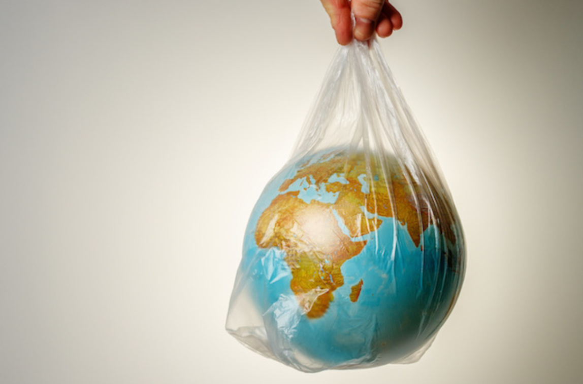 a hand holding the planet Earth in a plastic bag