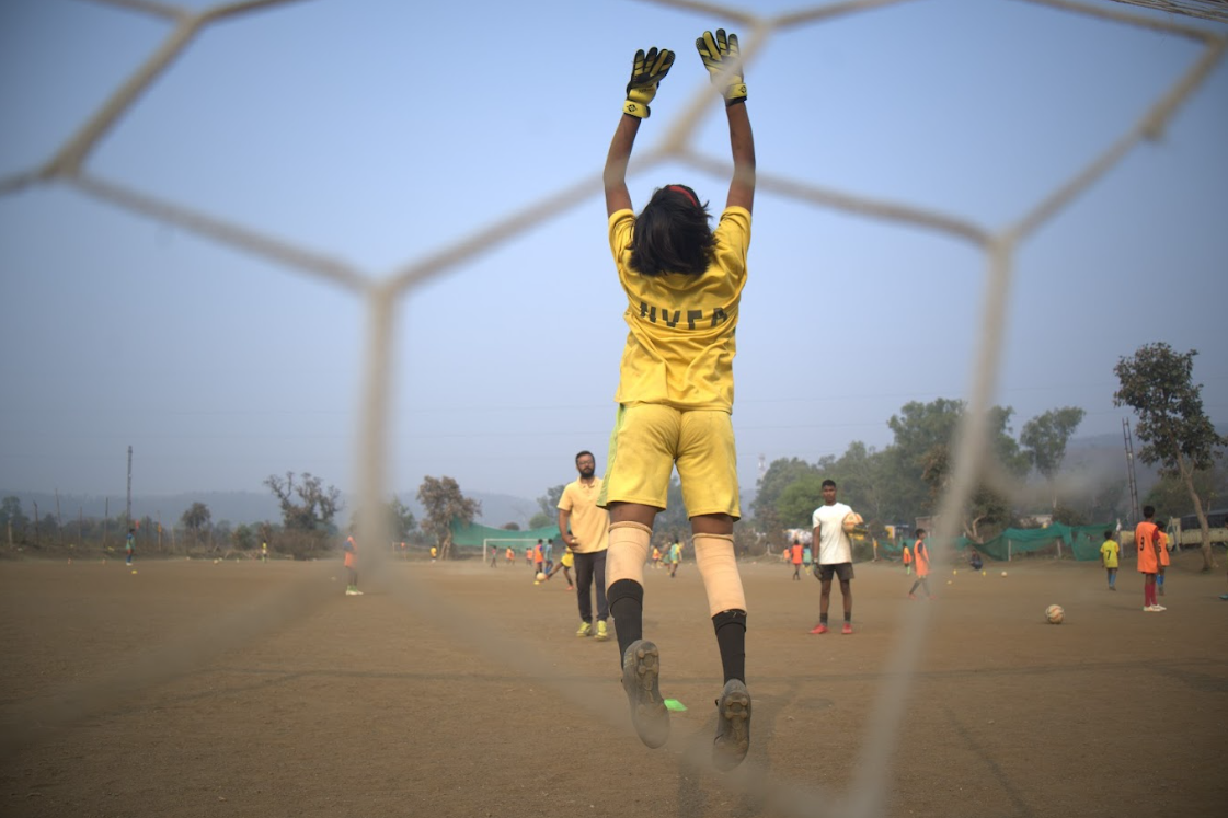 a female goalkeeper reaching for the ball