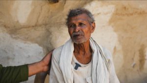 a farmer looking sad with a person's hand on their shoulder