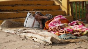 an old man sleeping outside on the ground