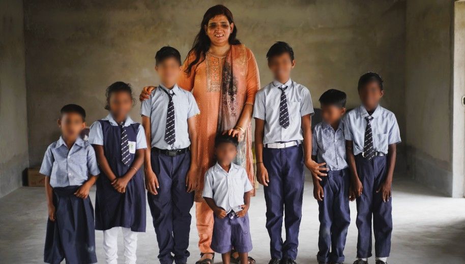 a lady standing with a group of school children