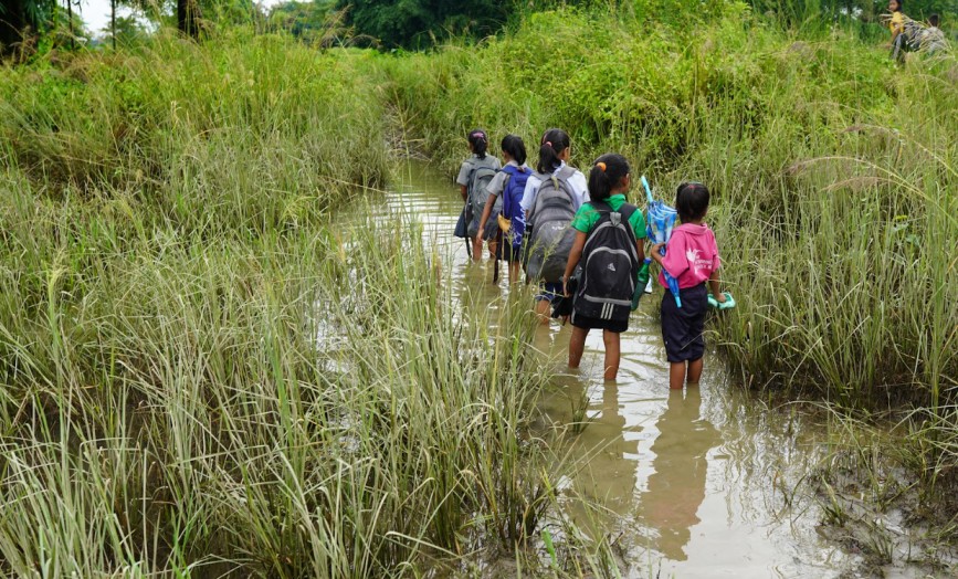 children on their way to school through flooded fields