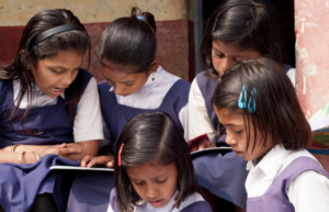 a group of schoolgirls reading something in a book