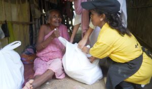 a person distributing food rations to an elderly woman