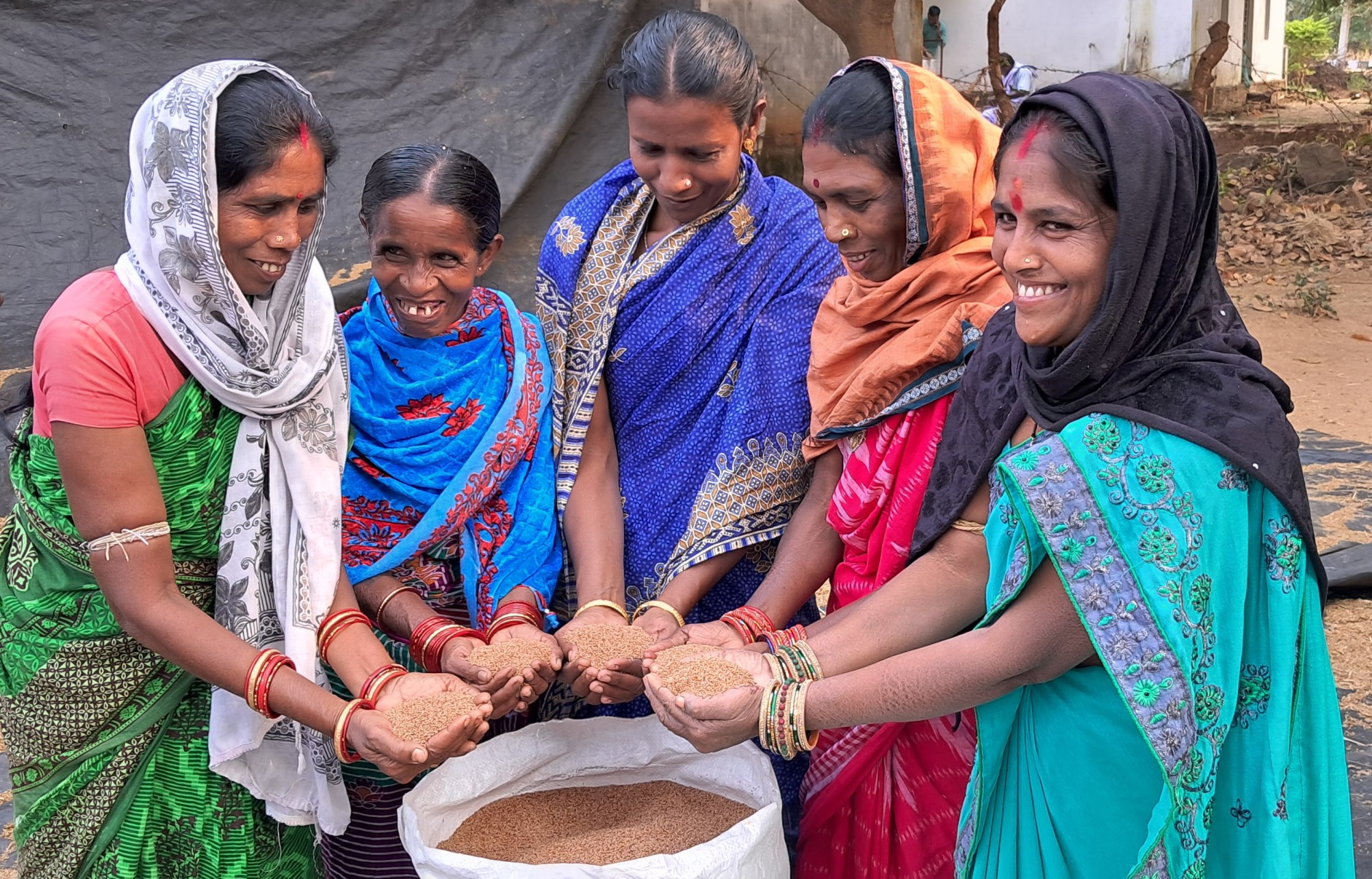 a group of women holding food grains