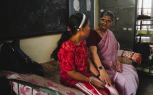 a woman and girl sitting on a bed and talking