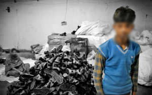 a child next to a pile of shoes looking at the camera