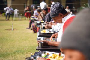 old people sitting outdoors eating a meal